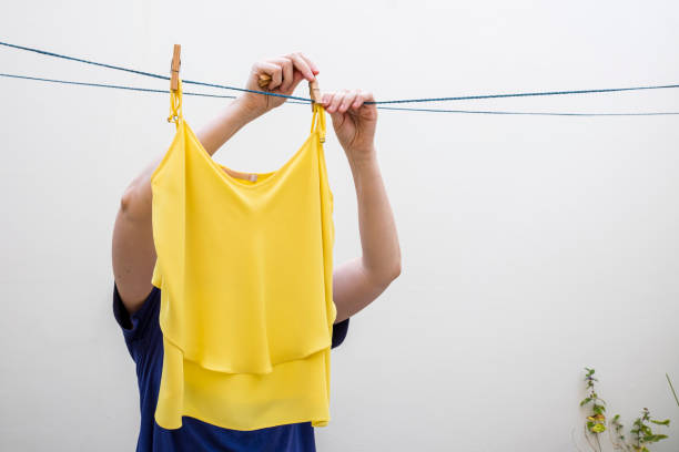 Woman extending clothes on clothesline to dry. Background with copy space.