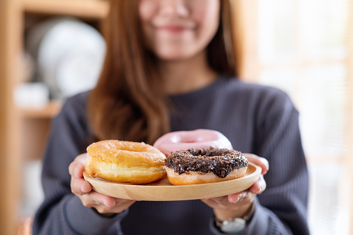 A young woman holding a plat of donuts in the kitchen at home