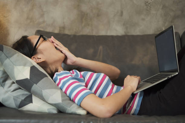 istock sleepy working at home, lying down, and yawn on living room's sofa. 1336211922