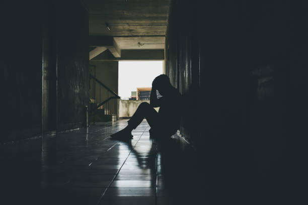 dramatische silhouette eines traurigen depressiven mannes, der mit dem kopf in den händen auf dem boden sitzt. trauriger mann, schrei, drama, einsames und unglückliches konzept. - mental abuse stock-fotos und bilder