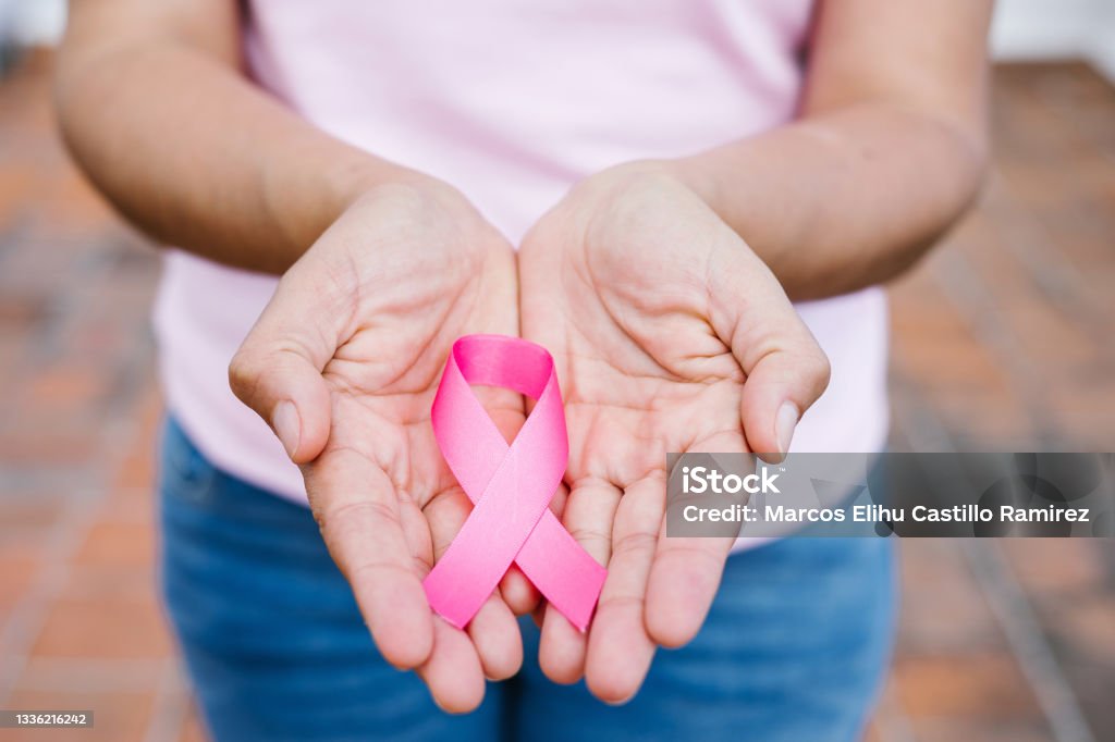 mãos mulher segurando fitas de conscientização do câncer de mama rosa com céu azul como fundo na América Latina - Foto de stock de Conscientização do câncer de mama royalty-free