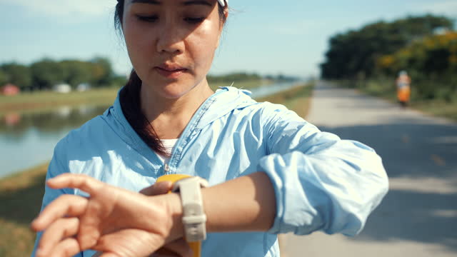 Woman stops jogging to look at her smart watch