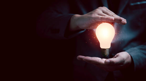 istock Businessman gesture protecting glowing lightbulb with copy space for creative thinking idea and problem solving concept. 1336217484