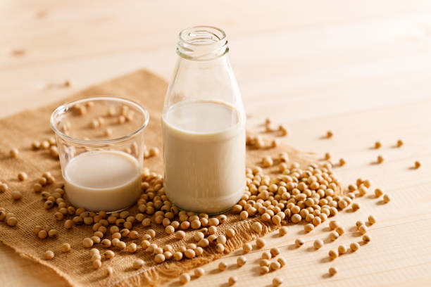 sojamilch in einer flasche auf holztisch - soymilk stock-fotos und bilder