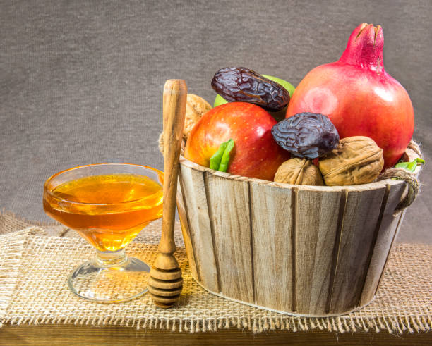 istock Honey, basket with apples and walnuts and pomegranate on wooden table 1336222264