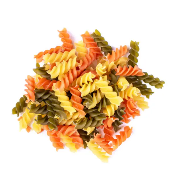 Photo of Heap of raw tricolor Fusilli gluten free pasta isolated on white background.