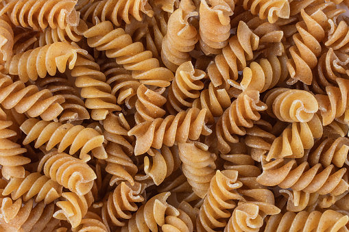 Organic raw gluten free buckwheat fusilli pasta background. Wholegrain gluten free macaroni. Food background.