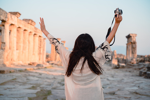 Fotógrafa turista chica levantar los brazos en la Puerta de Frontino en las antiguas ruinas de Hierápolis, Pamukkale photo