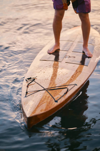istock Man's feet standing on the board in the water 1336230002