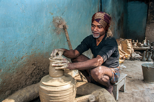 A potter is busy with pottery wheel to make earthenware at Panchmura,Bankura.