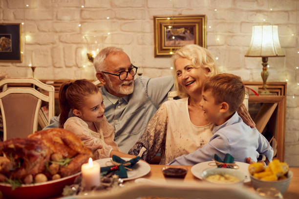 szczęśliwa para seniorów ciesząc się z wnukami przy stole w święto dziękczynienia. - dining table child grandparent grandchild zdjęcia i obrazy z banku zdjęć