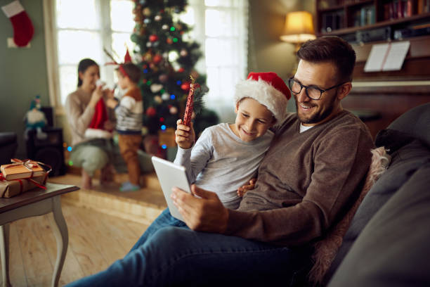 feliz pai e filho usando touchpad e fazendo chamada de vídeo no dia de natal em casa. - 3 6 months - fotografias e filmes do acervo