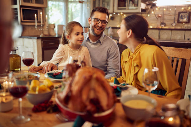feliz familia hablando durante la comida de acción de gracias en la mesa del comedor. - noviembre fotos fotografías e imágenes de stock