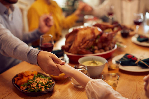 primo piano di padre e figlia che pregano durante il pasto di famiglia il giorno del ringraziamento al tavolo da pranzo. - benedizione foto e immagini stock