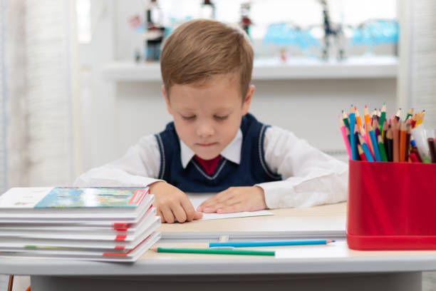 istock A cute first-grader boy in a school uniform at home while isolated at his desk makes a paper airplane during recess. Selective focus 1336231464