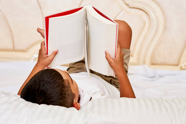 istock A cute child reading a book in the bed 1336233025