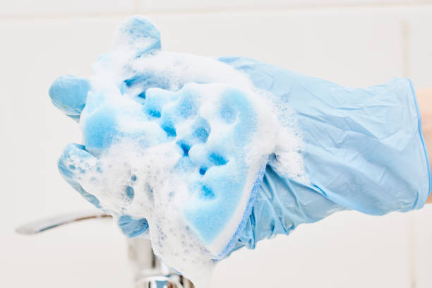 A hand holds foamy sponge A hand holds foamy sponge in the bathroom sink. Foamy cleaning sponge in a hand water sanitation worker washing faucet stock pictures, royalty-free photos & images