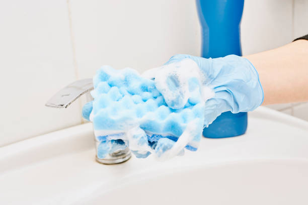 A hand holds foamy sponge A hand holds foamy sponge in the bathroom sink. Foamy cleaning sponge in a hand water sanitation worker washing faucet stock pictures, royalty-free photos & images