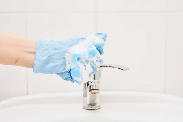 A hand holds foamy sponge A hand holds foamy sponge in the bathroom sink. Foamy cleaning sponge in a hand water sanitation worker washing faucet stock pictures, royalty-free photos & images