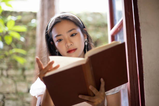 istock Young asian women reading a book by window 1336240386