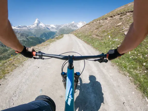 POV from male mountain biker on dirt trail in the Swiss Alps, mountain landscape. Handlebar view. Switzerland