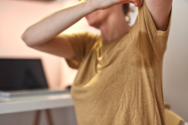 Woman with excessive armpit sweatiness and shirt stain. stock photo