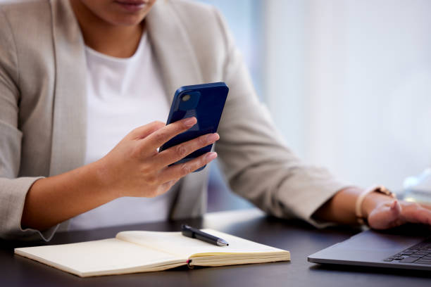 istock Cropped shot of a young businesswoman using a cellphone while making notes at her desk in a modern office 1336244359