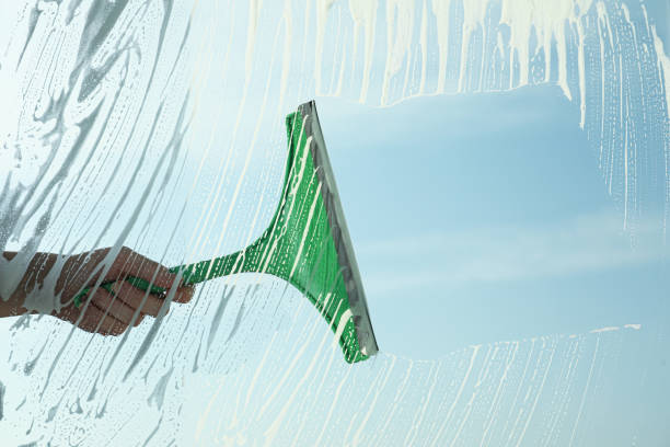 istock Woman cleaning window with squeegee on spring day, closeup 1336244675
