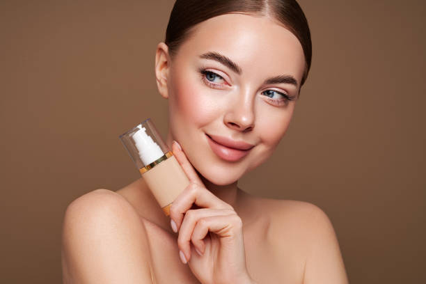 portrait belle jeune femme avec bouteille de fond de teint - make up foundation cosmetics face powder photos et images de collection