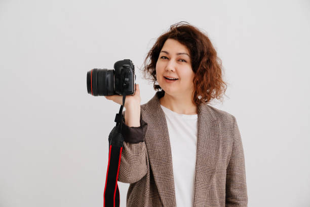 istock attractive brunette woman in checkered jacket on a white background with camera 1336249660