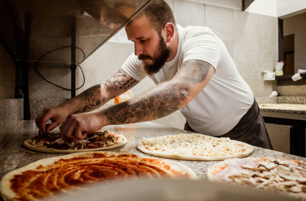 pizzaiolo che lavora in cucina - pizzeria foto e immagini stock