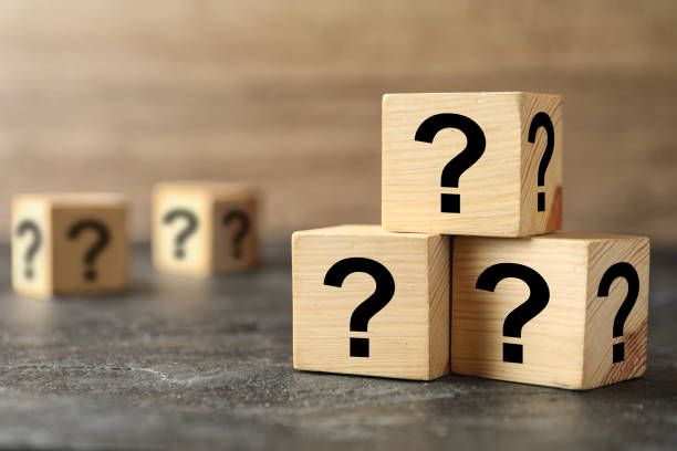 istock Wooden cubes with question marks on grey stone table, closeup. Space for text 1336250702