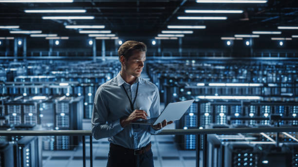 istock Portrait of IT Specialist Uses Laptop in Data Center. Server Farm Cloud Computing Facility with Male Maintenance Administrator Working on Cyber Security and Network Protection. 1336250768