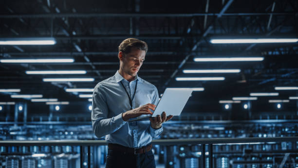 istock Portrait of IT Specialist Uses Laptop in Data Center. Server Farm Cloud Computing Facility with Male Maintenance Administrator Working. Cyber Security and Network Protection. 1336250770