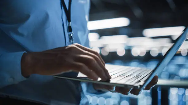 Photo of Data Center Programmer Using Digital Laptop Computer, Maintenance IT Specialist. Cloud Computing Server Farm System Administrator Working on Cyber Security for Iaas, saas, paas. Closeup Focus on Hands