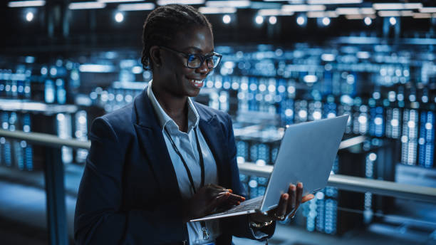 programmeur de centre de données utilisant un ordinateur portable, spécialiste informatique de maintenance. dans la ferme de serveurs de cloud computing administrateur système souriant travaillant sur la cybersécurité pour iaas, saas, paas. - data center computer programmer women photos et images de collection