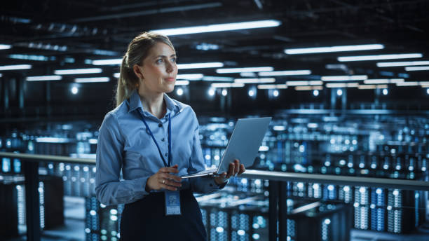istock Portrait of IT Specialist Using Laptop in Data Center. Big Server Farm Cloud Computing Facility with Female System Administrator Monitoring. Cyber Security, Network Protection Services. 1336251059