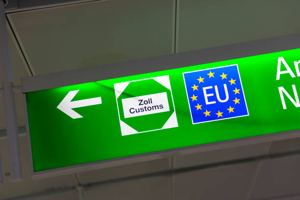 Green airport sign showing EU and customs symbols with an arrow pointing left.