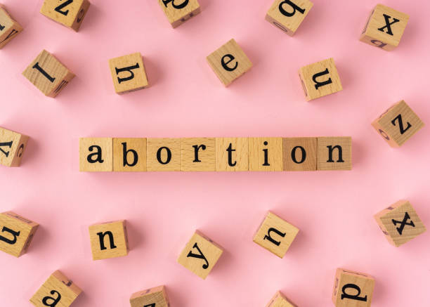 parola di aborto su blocco di legno. vista piatta su sfondo rosa chiaro. - aborto foto e immagini stock