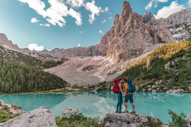 Couple hiking and kissing  in the Dolomites Italy. Beautiful Lake Sorapis Lago di Sorapis in Dolomites, popular travel destination in Italy. Blue green lake in Italian Dolomites.