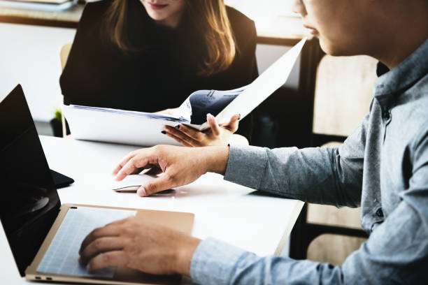 istock Focus on the male business owner using a computer mouse, while woman is browsing through the archives to find profitability information for the company. 1336253400