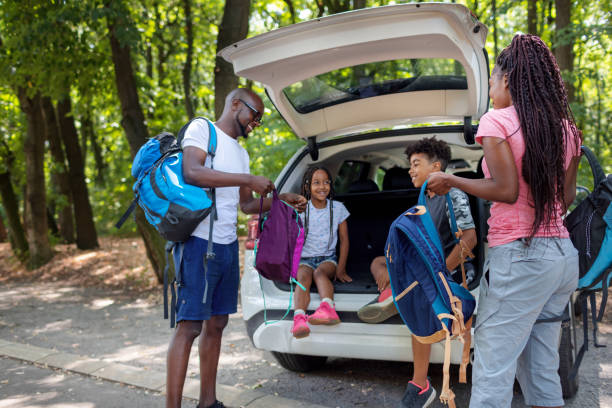 junge afrikanische familie bereitet sich vom auto aus auf das wandern vor - road trip stock-fotos und bilder