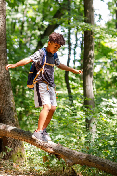 Cute African Boy Balancing On Log In The Wood stock photo