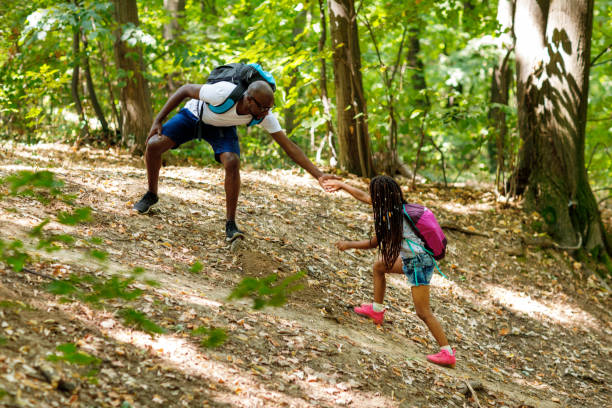 istock African Man Pulling His Daughter By The Hand While Walking In The Forest 1336254020