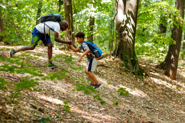 istock African Man Pulling His Son By The Hand While Walking In The Forest 1336254040