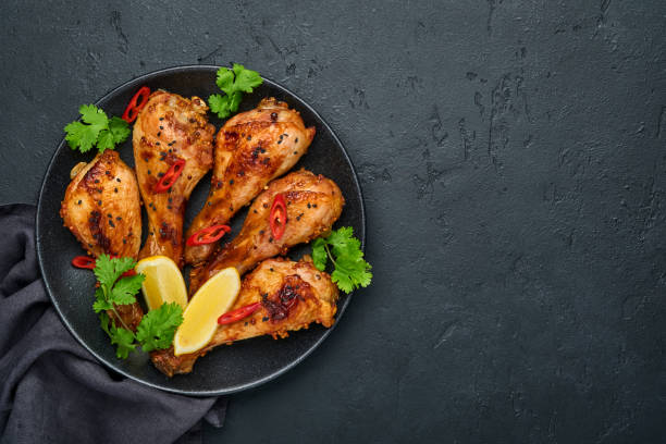istock Grilled chicken drumsticks or legs or roasted bbq with spices and tomato salsa sauce on a black plate. Top view with copy space. 1336257621