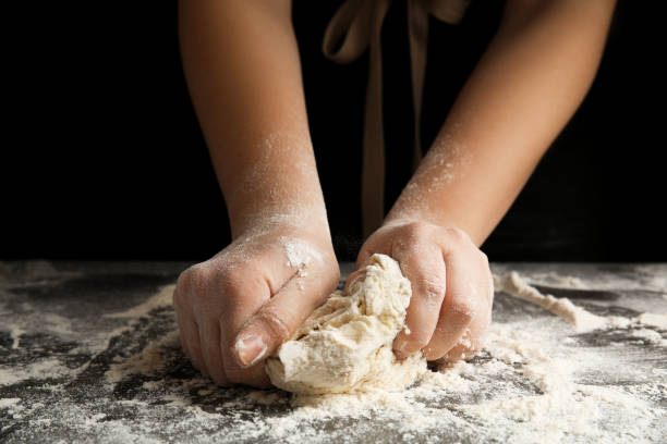 istock Woman kneading dough for pizza at grey table, closeup 1336264279