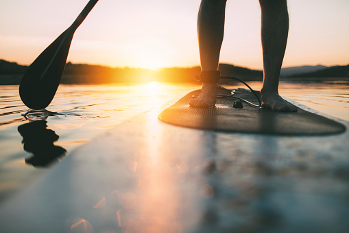 Close up of standup paddleboard on quiet lake at sunset.