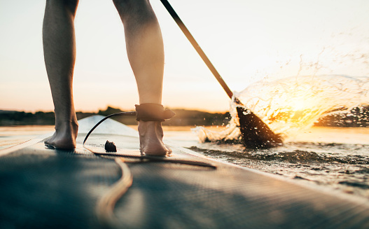 Close up of standup paddleboard on quiet lake at sunset.