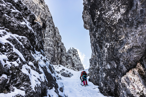 Solo hiker walking on a gully snowed